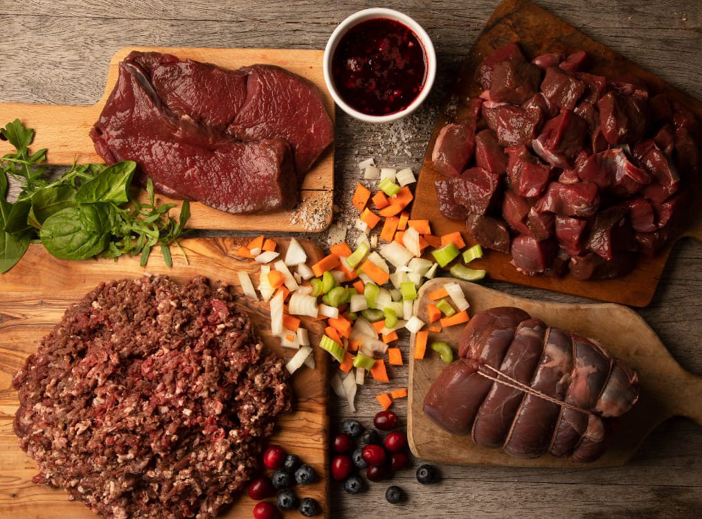 A selection of steaks, roasting joints, mince and diced meat on wooden chopping boards.