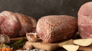 Selection of pork roasting joints on wooden chopping boards.